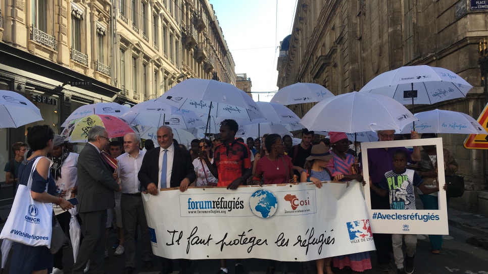 A l'occasion de la Journée mondiale du réfugié, le 20 juin, le HCR France a participé à la 15ème édition de la Marche des Parapluies à Lyon avec d'autres associations qui oeuvrent en faveur de l'accueil et de l'intégration des réfugiés. Les participants ont défilé dans la rue avec un parapluie blanc, symbole de l'abri et de la protection dont doivent bénéficier tous les réfugiés.
En première ligne (de gauche à droite) figurent Georges Képénékian, Maire de Lyon, Ruba Khatib, réfugiée syrienne et autoentrepreneur ainsi que Jean-François Ploquin, Directeur de l'association Forum Réfugiés – Cosi.