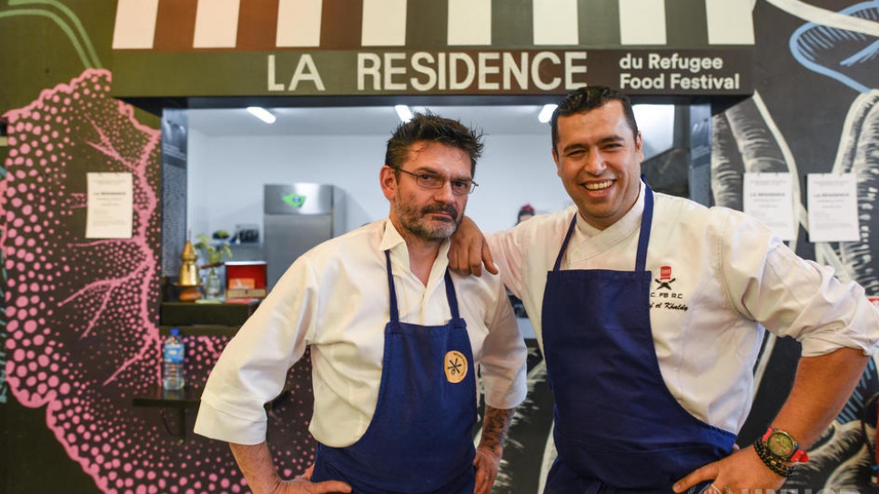 Le chef syrien réfugié Mohammad El Khaldy pose avec son homologue français Stéphane Jego devant la Résidence du Refugee Food Festival à Ground Control à Paris le 24 juin, lors de la clôture de l'évènement. La Résidence est le premier restaurant et lieu de formation dédié aux chefs réfugiés. 