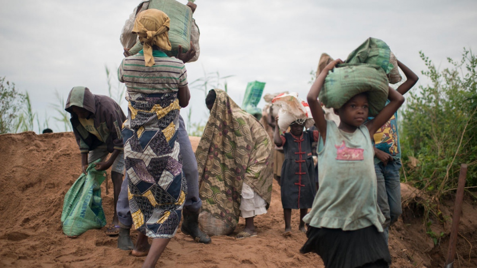 Après avoir rempli les sacs de 25 kilos de sable, les femmes et les enfants déplacés les portent jusqu'aux chantiers de construction de Kalemie, la capitale de la province du Tanganyika, en RD Congo. 