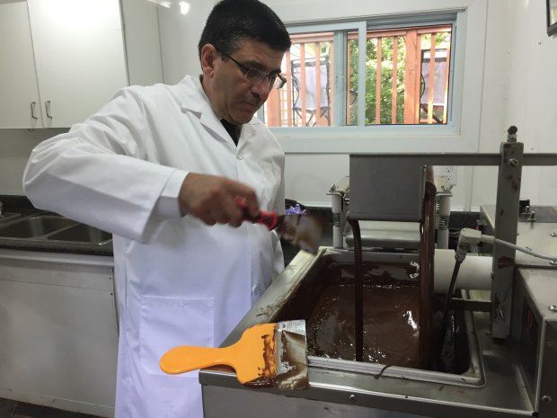 Un homme syrien dans un blason de laboratoire mélange du chocolat dans un laboratoire de chocolat.