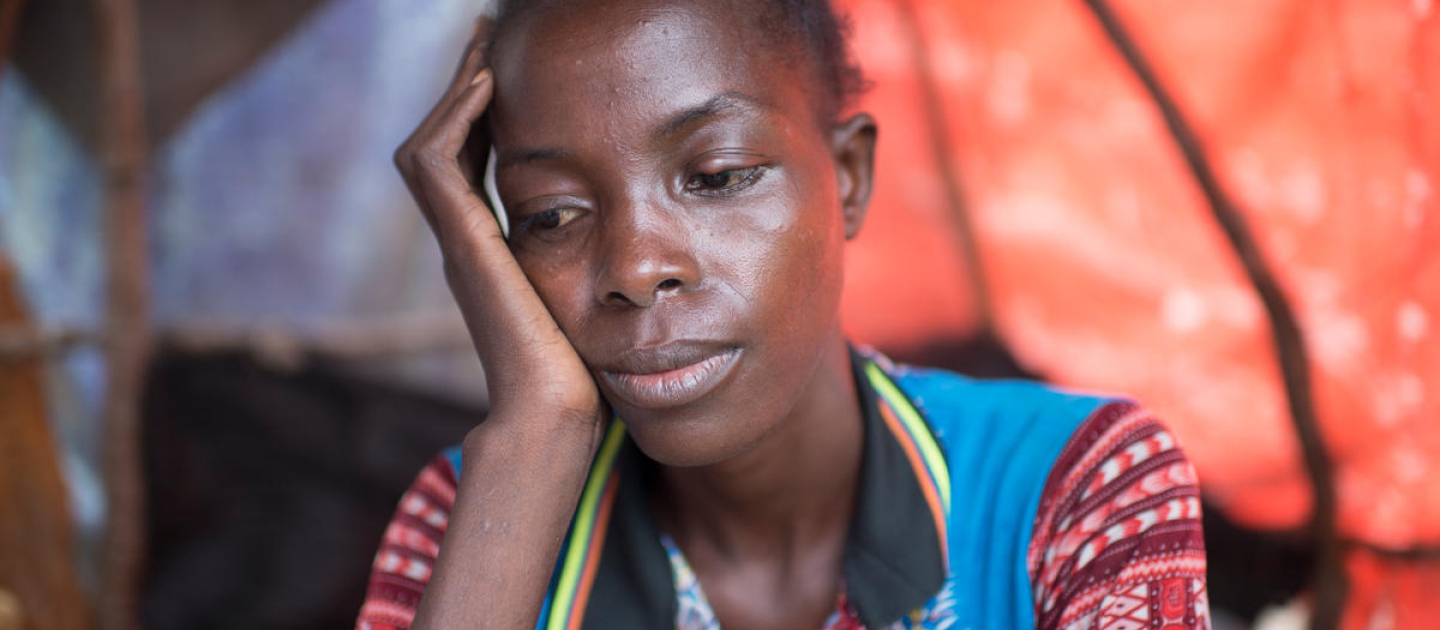 A Congolese woman in a colourful shirt rests her head in one hand as she thinks about the fate of her kidnapped children.