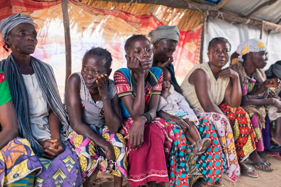 Several colourfully dressed Congolese women sit in a row, lamenting the kidnapping of their children.