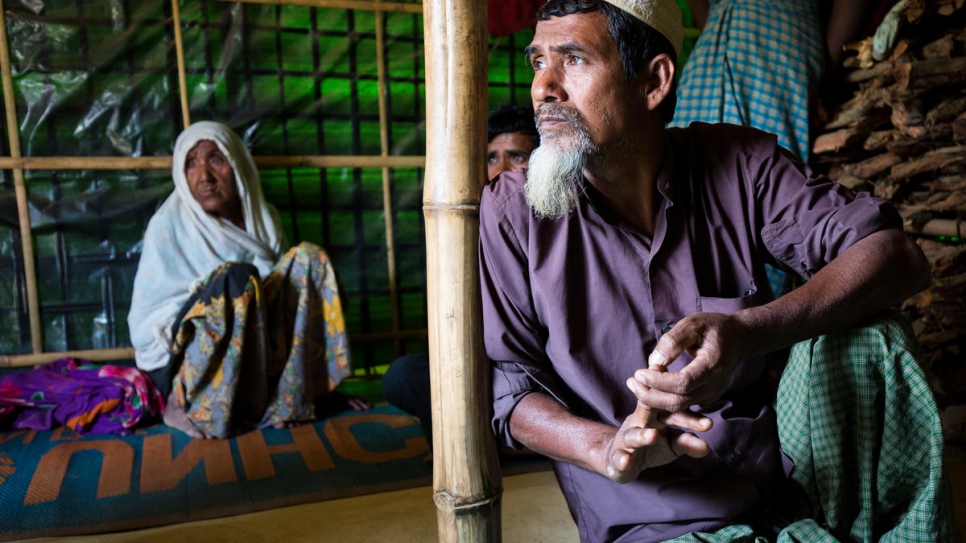 Oli Ahmed looks out the door of the family's shelter as his mother, Gul, looks on.