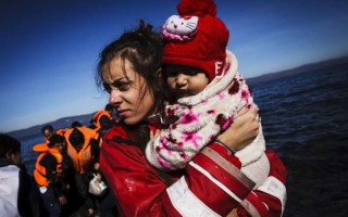 A volunteer on the Greek Island of Lesvos gathers a baby girl in her arms, moments after her family arrived in an inflatable boat.