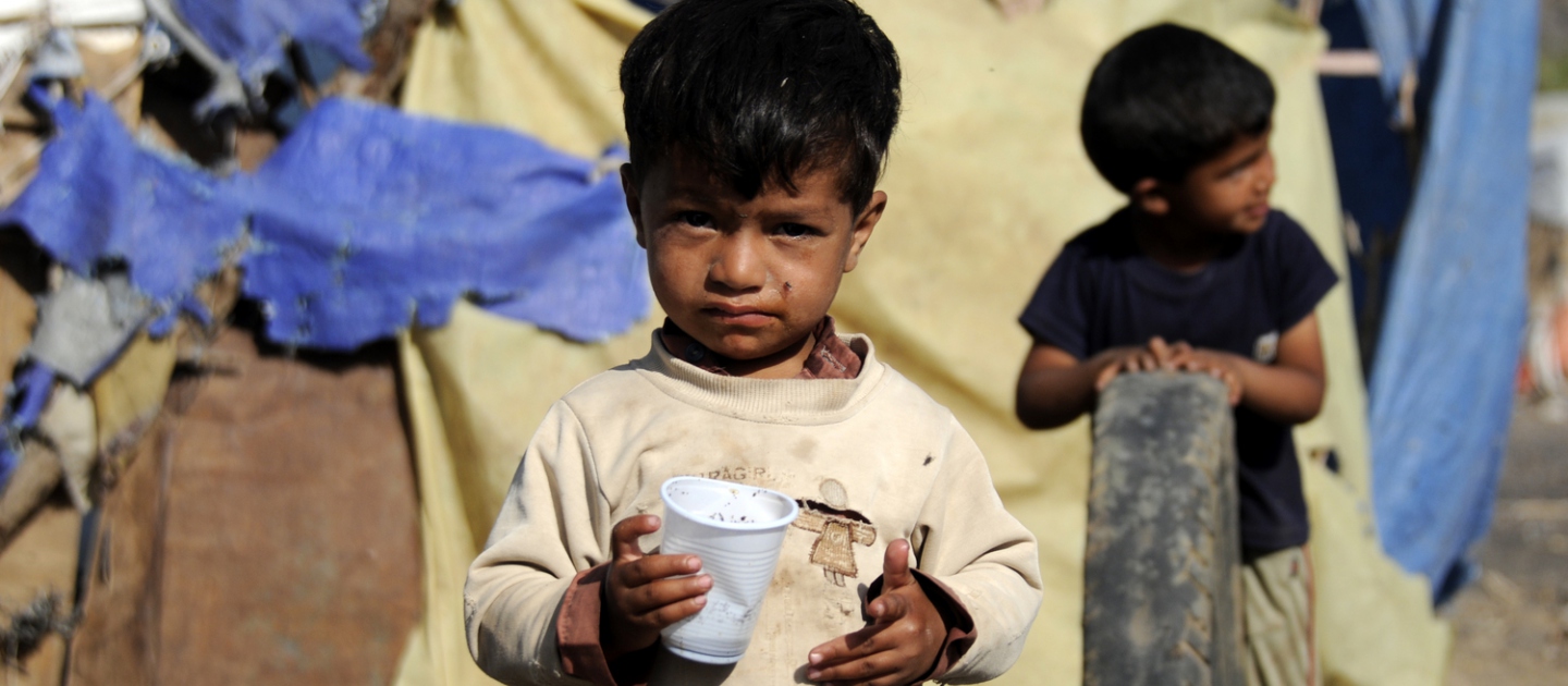 Un jeune enfant se trouve devant l'abri de fortune de sa famille dans l'installation de Dharawan, au Yémen. 