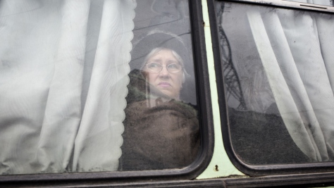 Une femme attend au chaud dans un bus à un poste de contrôle à Marïnka, en Ukraine. 