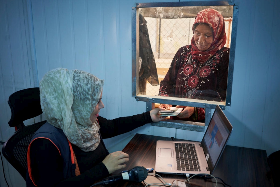 لاجئون سوريون يقفون في الطابور للحصول على المساعدات النقدية لفصل الشتاء في مخيم الزعتري للاجئين في الأردن، نوفمبر 2017. تتيح المساعدة للاجئين شراء لوازم التدفئة والعزل والثياب الدافئة
