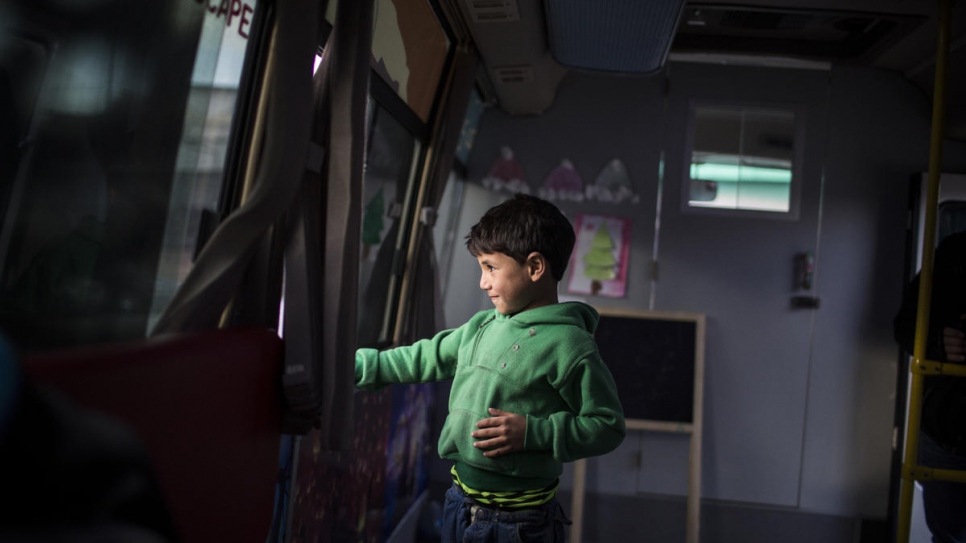 Ezzo, a 6-year-old Syrian refugee from Aleppo, looks through the window of the "Fun Bus".