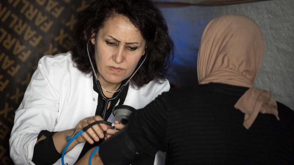 Nagham Nawzat Hasan counsels and treats a Yazidi woman at an informal tented settlement for displaced people in Duhok Governorate in the Kurdistan region of northern Iraq.