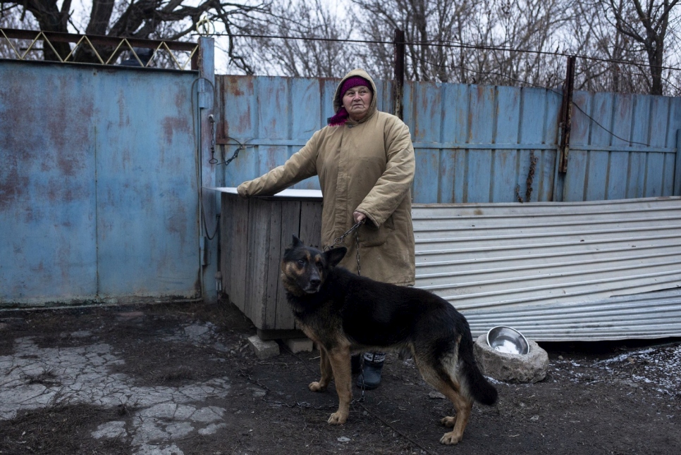 Stefania et son chien devant la maison du voisin où elle réside à Mykolaïv, Donetsk. 
