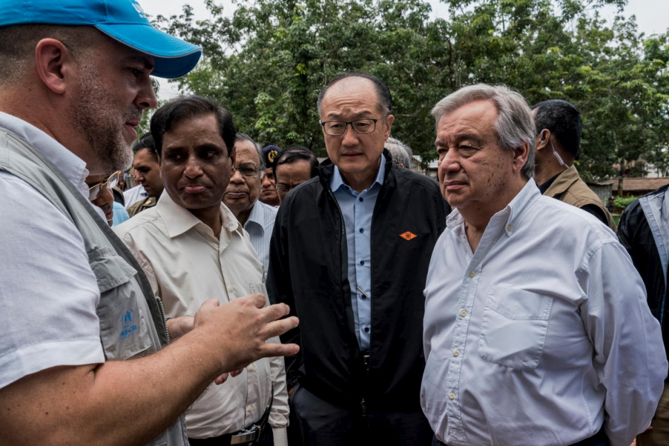 الأمين العام للأمم المتحدة أنطونيو غوتيريس (يمين) ورئيس مجموعة البنك الدولي جيم يونغ كيم (الثاني من اليمين) يستمعان إلى إحاطة من أحد مسؤولي المفوضية في مركز عبور تابع للمفوضية للاجئين الروهينغا الواصلين حديثاً في كوتوبالونغ، بنغلاديش.