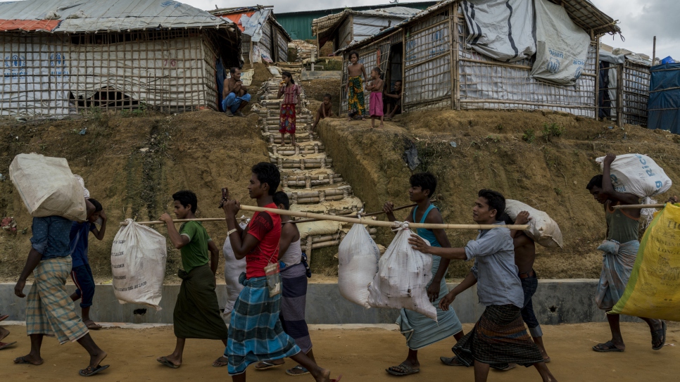 Des réfugiés rohingyas qui vivaient dans des tentes risquant d'être emportées par des glissements de terrain transportent leurs possessions vers de nouveaux abris situés dans la zone d'extension 4, récemment ouverte au camp de réfugiés de Kutapalong au Bangladesh. 