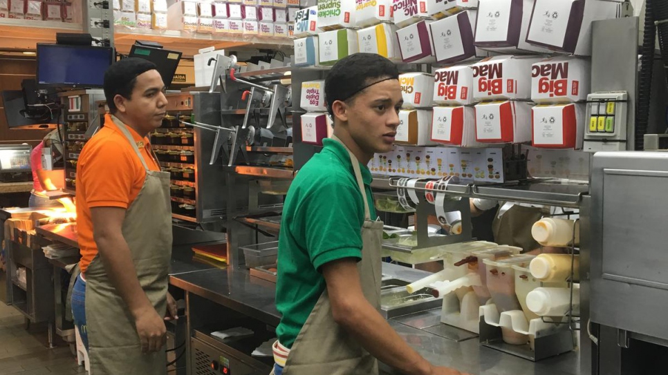 Jefferson, 18, (right) from Venezuela at the McDonald's where he now works in São Paulo, Brazil. 