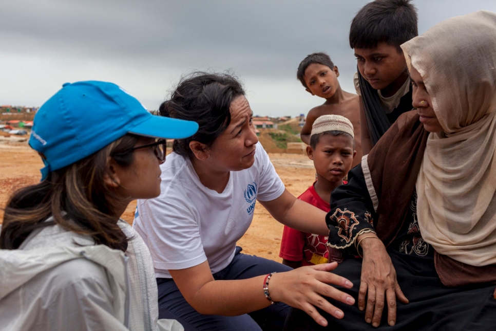 Outside. A women and three children talk with two UNHCR staff.