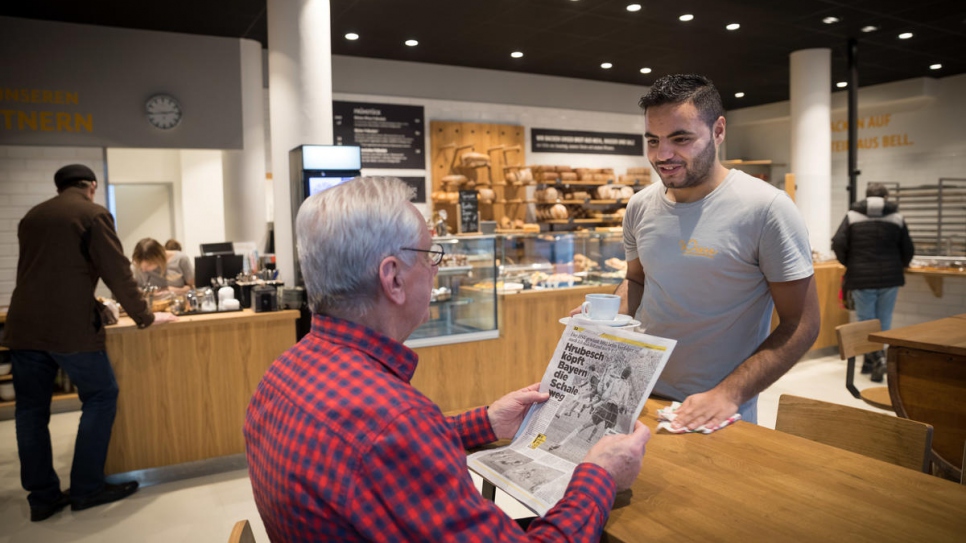 Mohamad practices his German with a customer at the bakery.