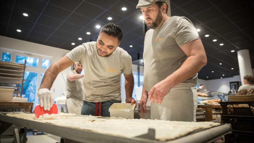 Master baker Björn Wiese (right) teaches Mohamad how to prepare the dough.