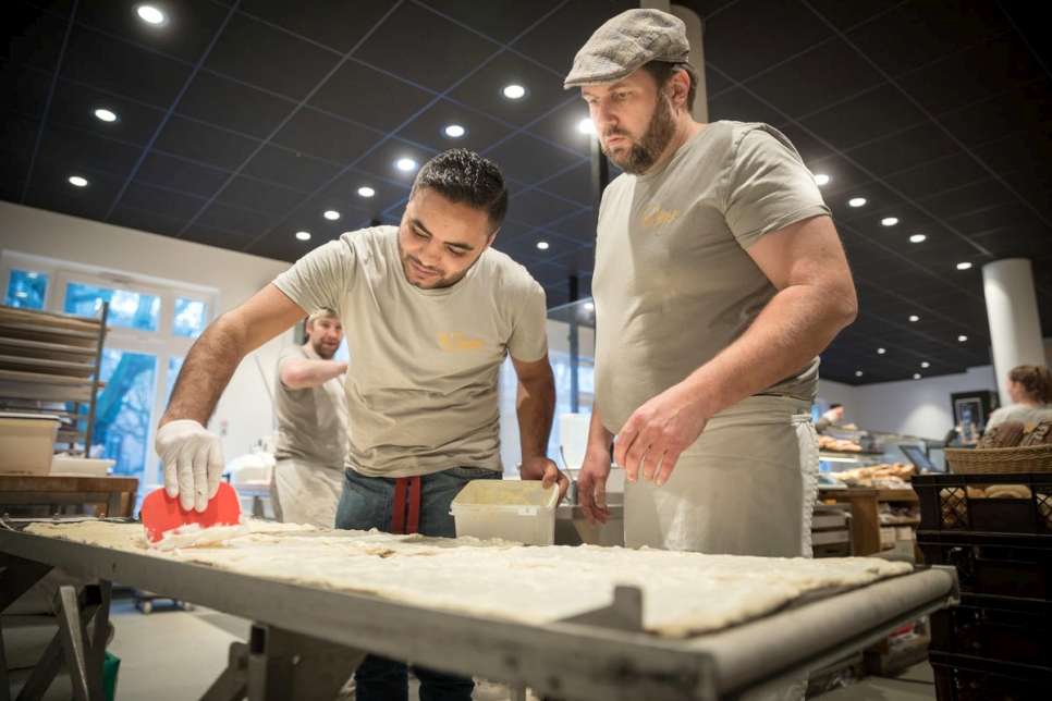 El maestro panadero Björn Wiese (derecha) le enseña a Mohamad cómo preparar la masa. 