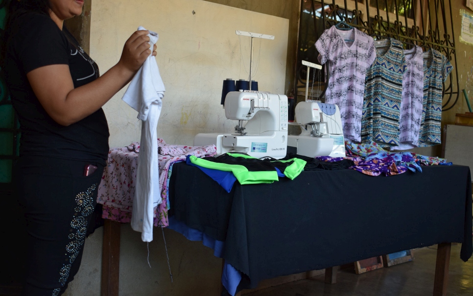 Joven muestra una camisa realizada en uno de los emprendimientos que proporciona servicios de serigrafía y estampado.