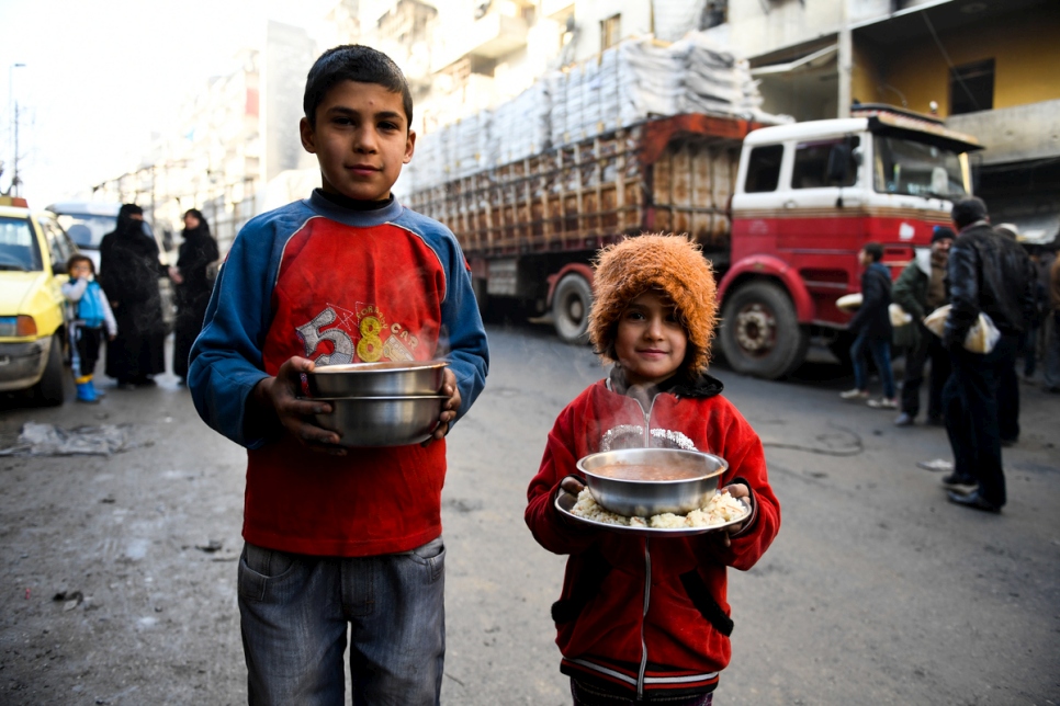 Displaced children carry cooked meals provided by a local charity in the Al-Mashatiyeh neighborhood of east Aleppo, Syria, where UNHCR and its partners are distributing key relief items. 