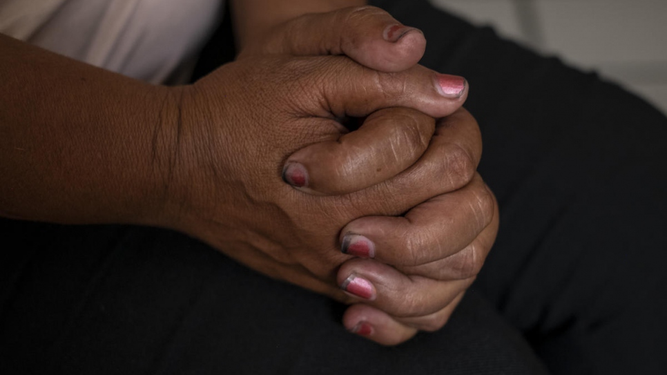 Luisa presses her hands against each other as she explains the traumatic experience of sexual abuse she suffered in Honduras.