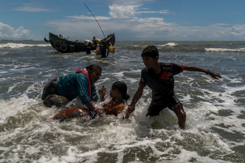 Des réfugiés rohingyas débarquent d'un bateau de pêche au milieu de l'eau, à l'approche de la plage de Dakhinpara, au Bangladesh. 