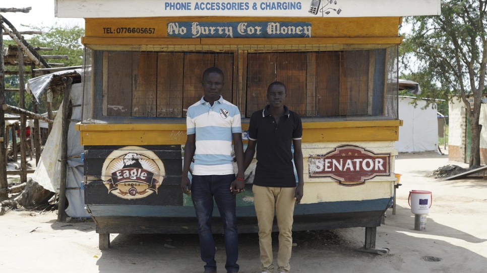 South Sudanese refugees stand in front of the phone shop they are opening soon.