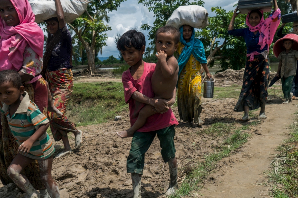 Un garçon rohingya porte son petit frère pour franchir la frontière avec sa famille en direction de Whaikhyang, au Bangladesh. 