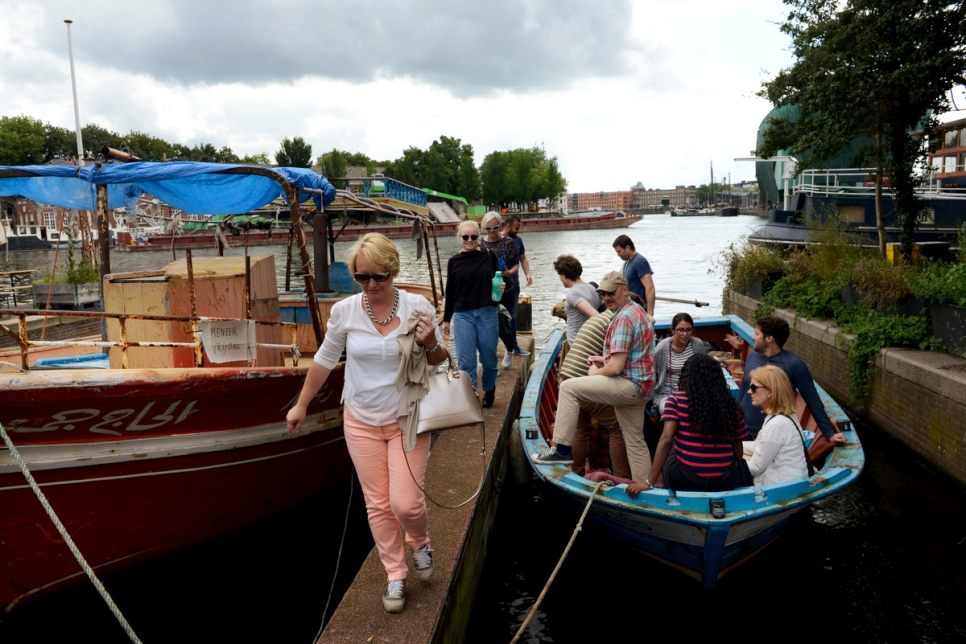 Les bateaux utilisés par les réfugiés pour atteindre la sécurité en Europe sont convertis en bateaux de tourisme sur les canaux d'Amsterdam, des réfugiés servant de guides. Le « Mister Friday » (à gauche) a transporté autrefois 282 réfugiés et migrants à travers la Méditerranée, tandis que le « Hedir » (à droite), qui signifie « Temps orageux », en a transporté 76. 