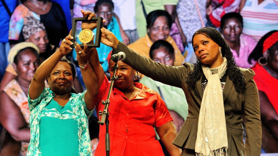 The Butterflies volunteers hold up the Nansen Award medalat the 2014 Nansen Refugee Award ceremony. 