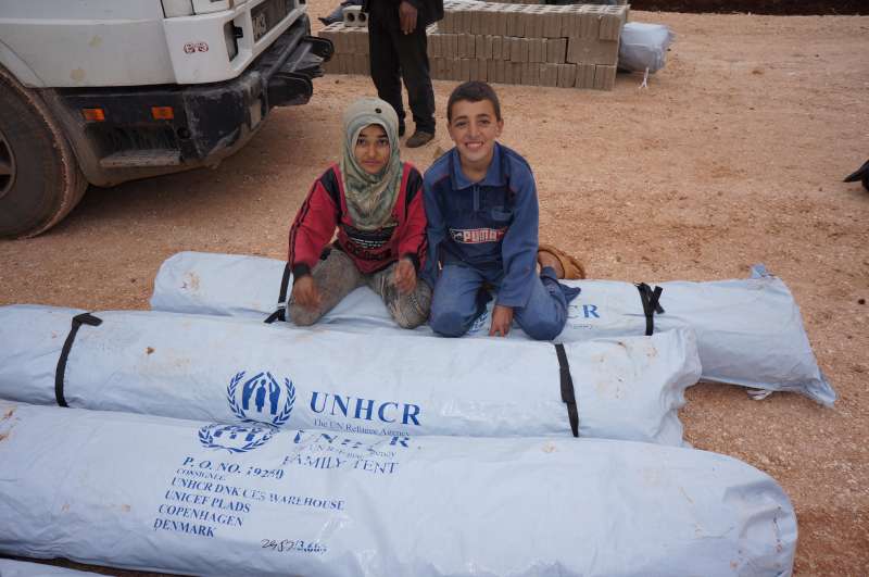 Displaced Syrian children sit on a UNHCR tent in Syria, February 2013 