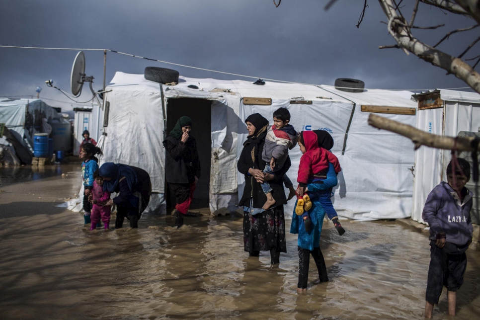 جورية رمضان، القادمة من دير الزور في سوريا، تسير في مخيم الدلهمية العشوائي المغمور بالمياه في وادي البقاع، لبنان.