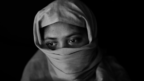 Black-and-white portrait of a 20-year-old Rohingya woman wearing a headscarf.