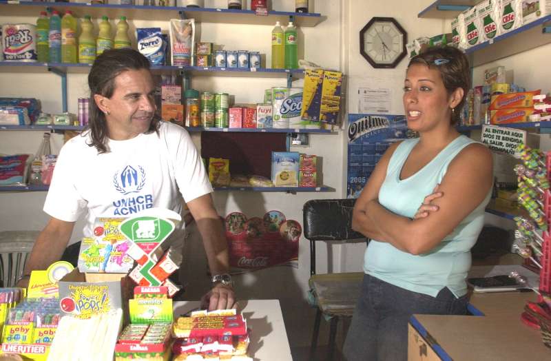 UNHCR Goodwill Ambassador Osvaldo Laport chats to a refugee in Argentina who received a small loan from UNHCR to help set up her own shop.