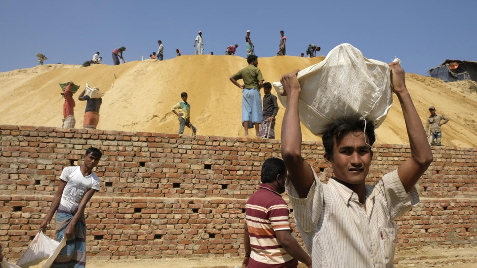 Rohingya refugees set to work building terraces on a hillside in Chakmarkul camp to prevent landslides and protect the road and shelters below from flooding.