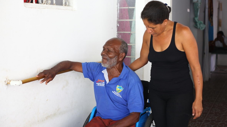 A Venezuelan woman supports a Colombian man in a wheelchair at Grandpa's House in Riohacha, Colombia.