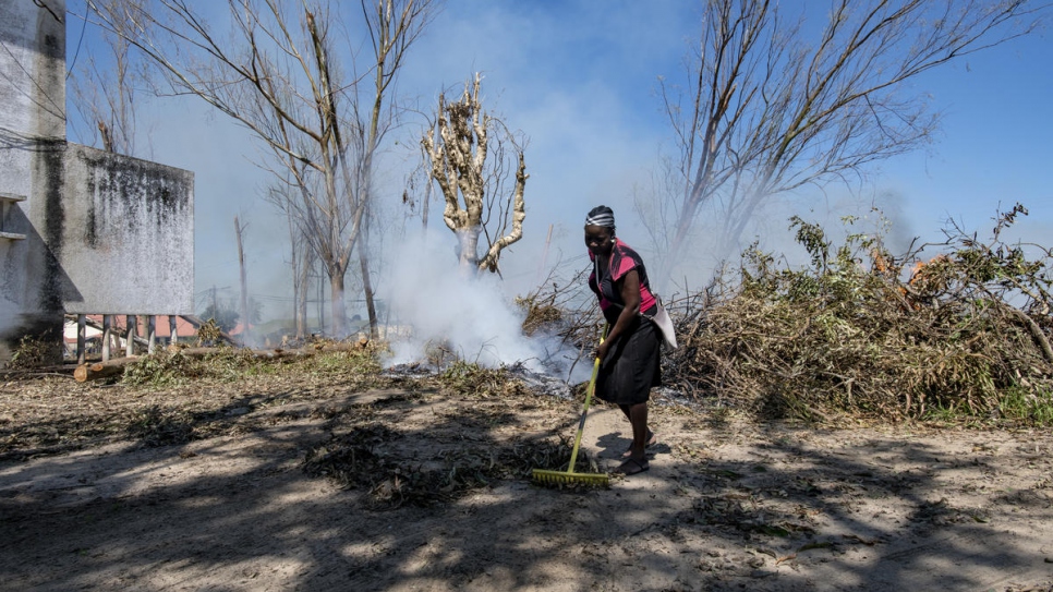 A woman sweeps the city streets of Dondo, Mozambique, cleaning and burning the branches and fallen leaves in the aftermath of Cyclone Idai.