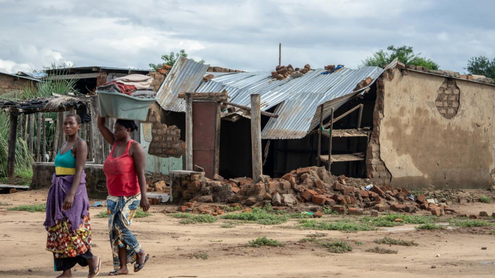 Two women walk past a house destroyed during Cyclone Idai's landfall at Tongogara refugee camp in Chipinge district, south-eastern Zimbabwe.
