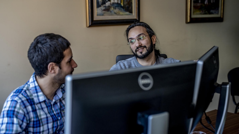 Mawaheb speaks with a colleague at his office. He works as a software engineer for an energy company in Belgrade.