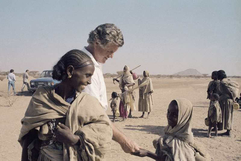 El senador Edward M. Kennedy sonríe y saluda a un joven refugiado no identificado en un campo del este de Sudán en 1984. Muchos de los refugiados habían caminado durante una semana para llegar al campamento desde Eritrea. 
