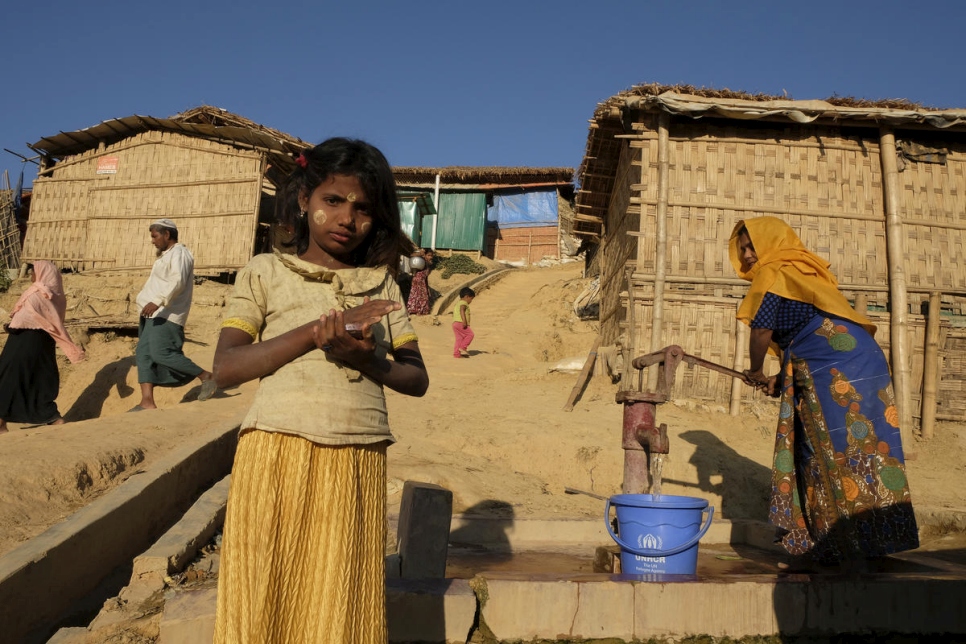 Mientras la vida del campamento continúa detrás de ella, Minara, una joven rohingya, se detiene a la luz del sol de la tarde en el campamento de refugiados de Kutupalong en Bangladesh. 