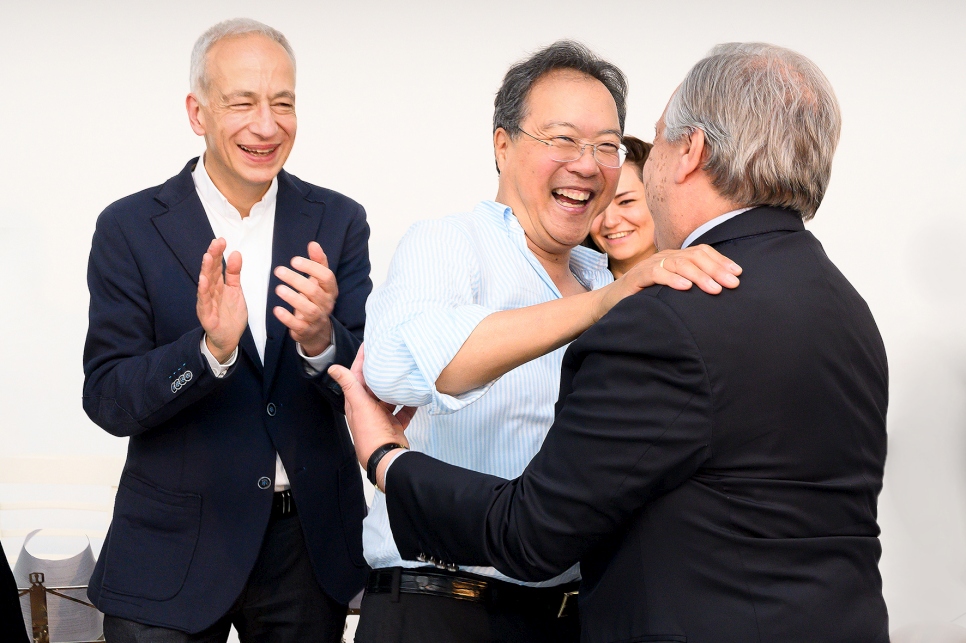 El violonchelista Yo-Yo Ma da la bienvenida al secretario general de la ONU, António Guterres, mientras el presidente de Caritas Austria, Michael Landau, observa. 