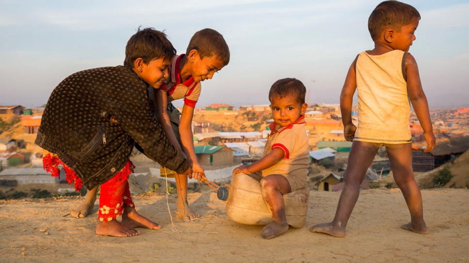 Niños jugando con "trineo" hecho con un envase de plástico en el asentamiento para refugiados de Kutupalong, en Bangladesh.