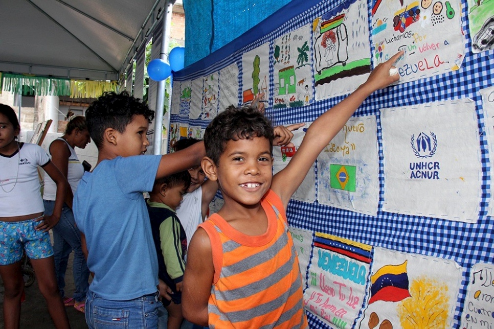 Niño venezolano muestra orgullosamente su diseño en el mural, realizado en el albergue São Vicente.