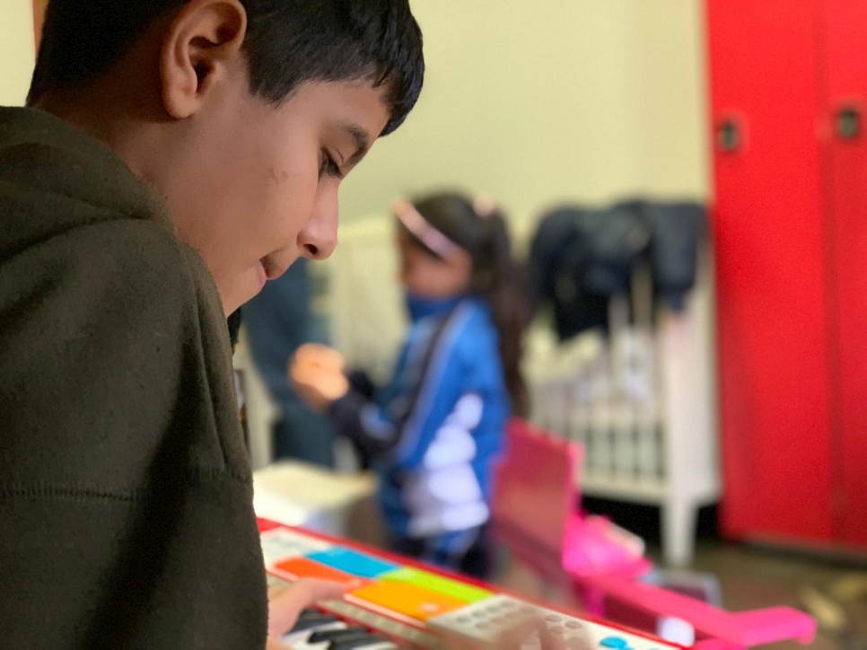 Shady toca con un piano donado a su familia, en un centro de alojamiento de emergencia para refugiados y solicitantes de asilo donde vive con su familia. Shady ha comenzado a ir a la escuela, donde podrá aprender español.