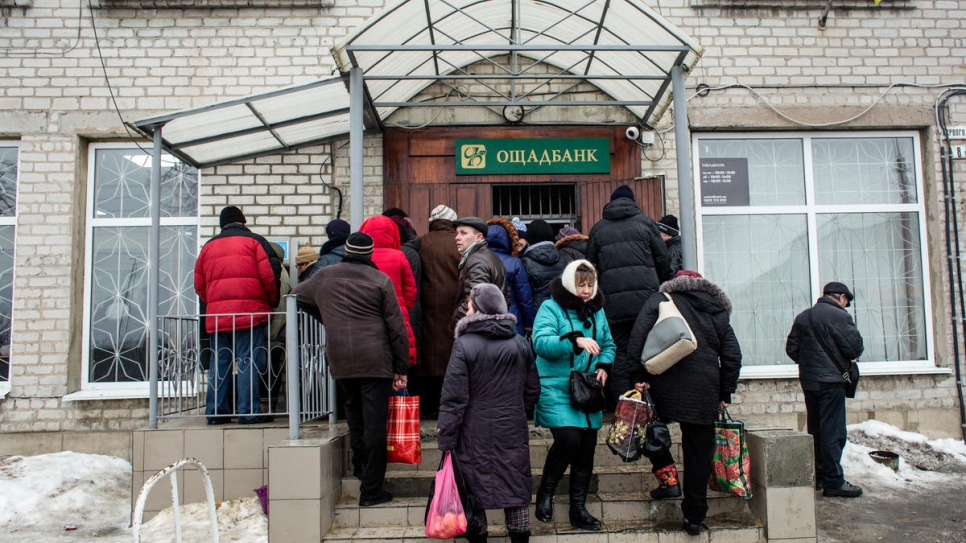 Jubilados esperan para retirar su pensión del banco estatal en Volnovaja.