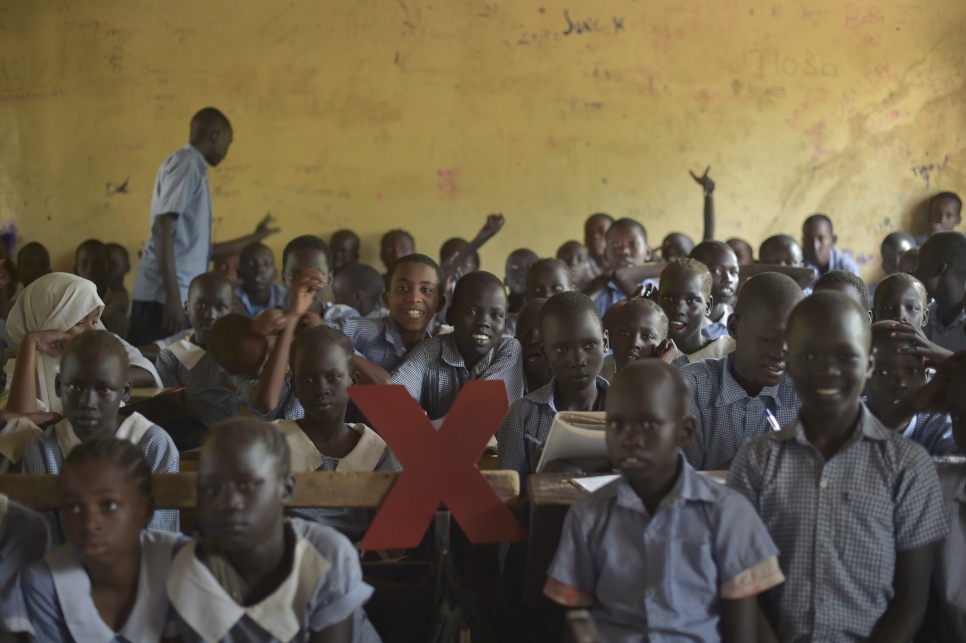 Niños y niñas en una escuela en el campamento de refugiados de Kakuma, en Kenia, jugando con el logo de TEDx.