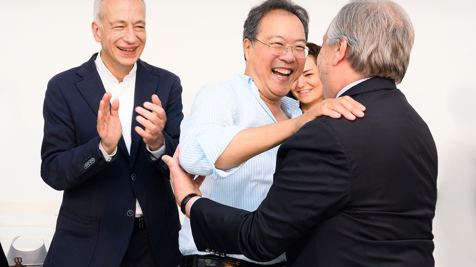 Cellist Yo-Yo Ma welcomes UN Secretary-General António Guterres, while the president of Caritas Austria, Michael Landau, looks on.