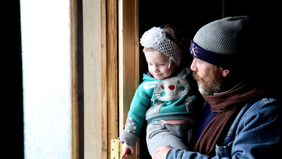 Jihad holds his two-year-old daughter, Habiba, in their recently-rehabilitated house in Homs. New doors and windows were provided by a local NGO with support from UNHCR.