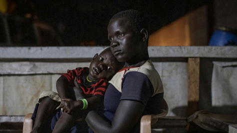 Une Sud-Soudanaise tient son enfant sur les genoux en attendant de recevoir leur repas et un hébergement dans le centre de transit d'Aru, province d'Ituri, République démocratique du Congo. 