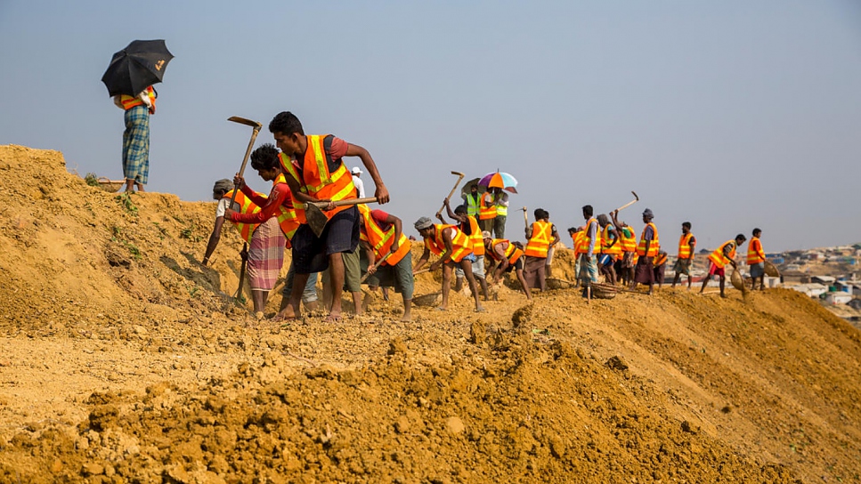 Los trabajadores nivelan una pendiente en un sitio al oeste del límite actual del asentamiento de refugiados de Kutupalong.